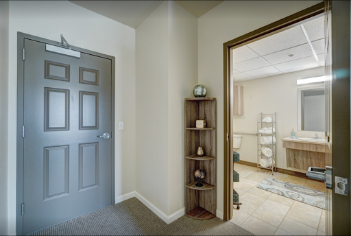 A view of a well-lit interior space featuring a hallway leading to a bathroom, complemented by decorative shelving.