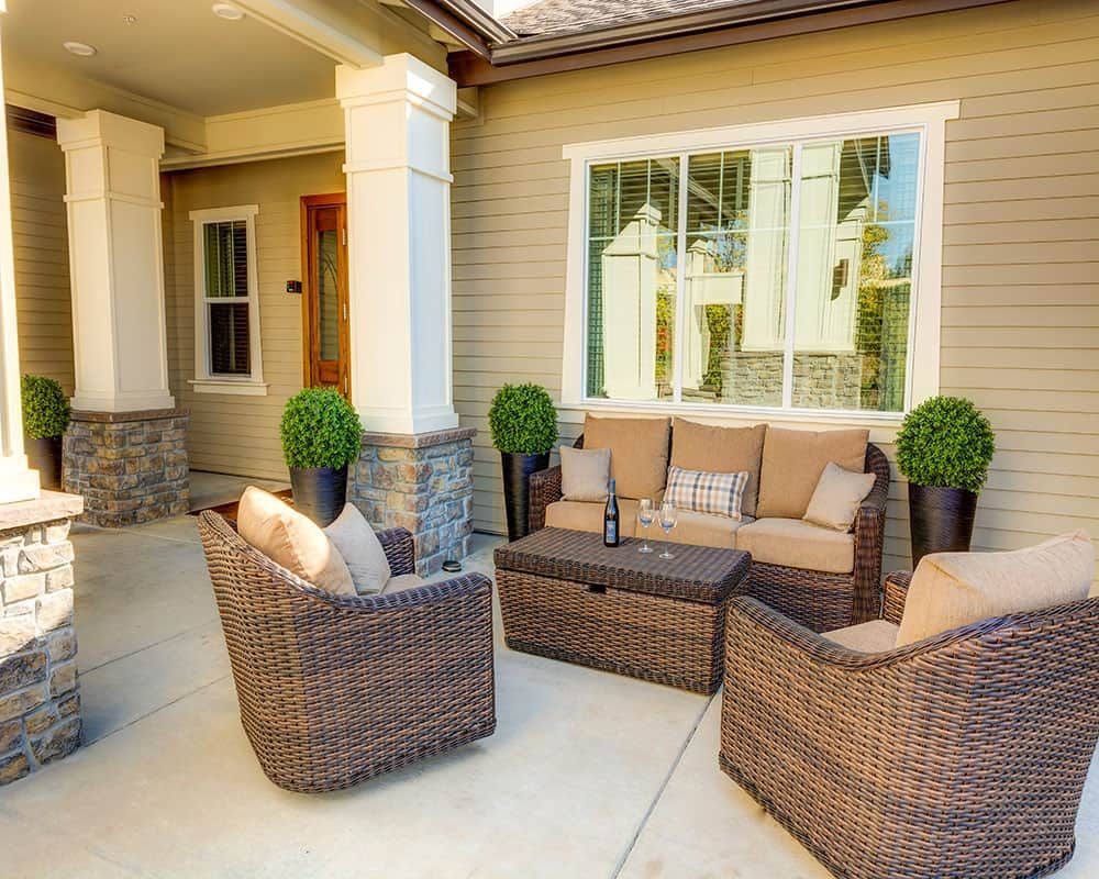 A cozy patio setup with wicker furniture and decorative plants.