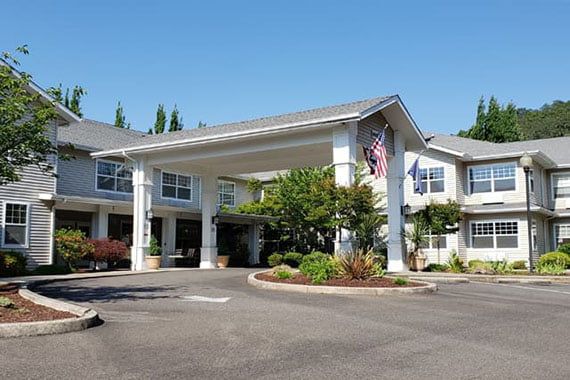A large building with an entrance canopy and surrounding landscaping, featuring flags at the front.