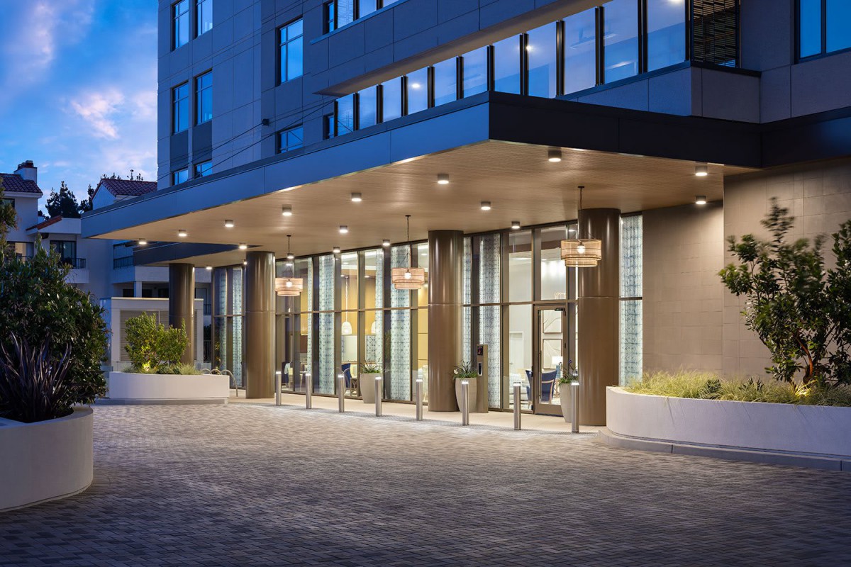 A modern hotel entrance illuminated at night with glass doors and sleek design.
