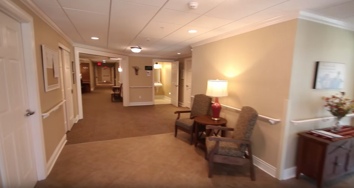 A well-lit hallway with comfortable chairs and a lamp.