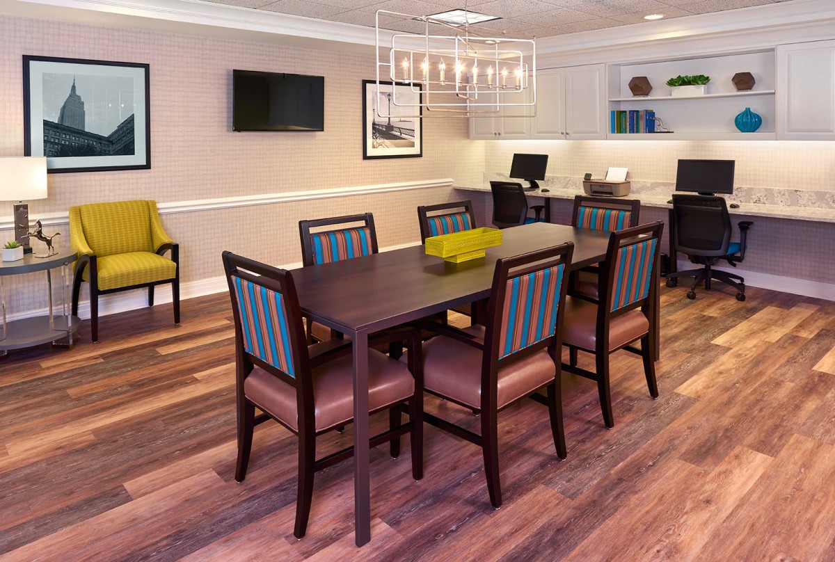 A modern dining room featuring a large table with chairs, elegant chandelier, and hardwood flooring.