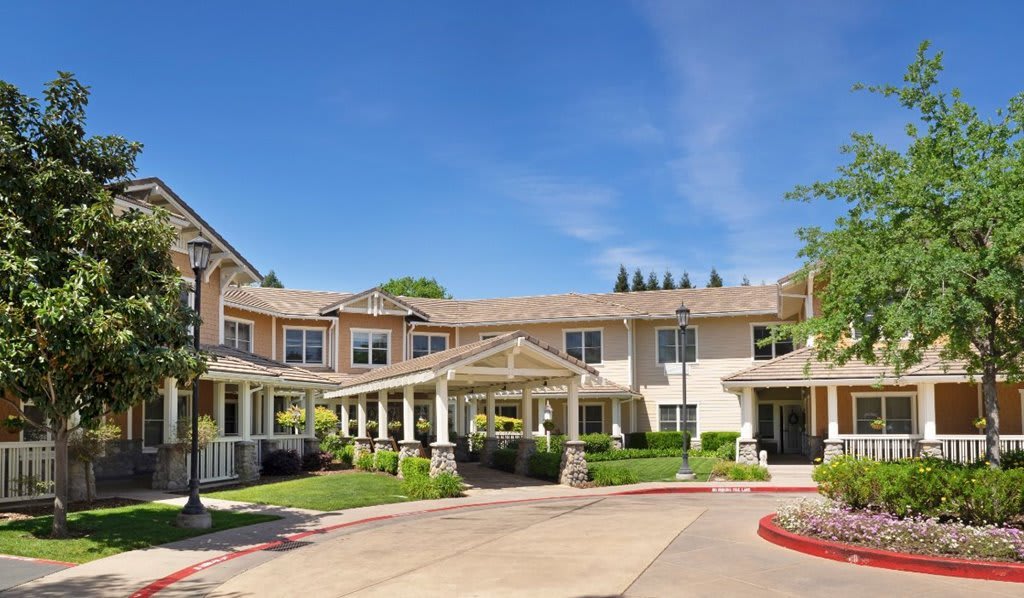 A two-story residential building with a covered entrance and landscaped surroundings on a sunny day.