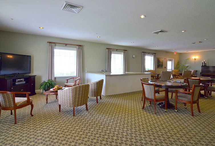 A spacious lounge area with comfortable chairs, tables, and a patterned carpet.