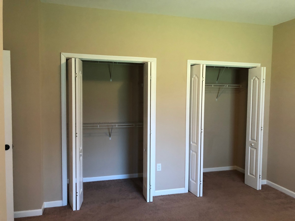An empty room with two open closets for storage.