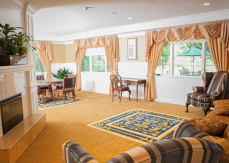 An elegantly furnished living room with large windows and warm-toned curtains.