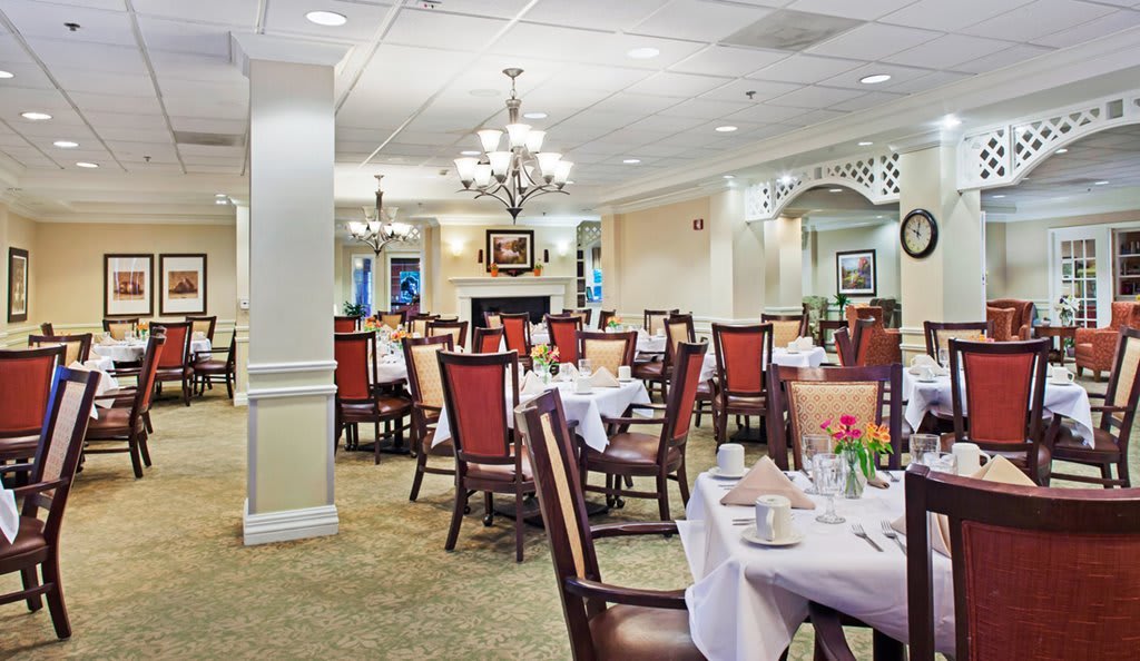 An elegant dining room with neatly arranged tables and chairs, featuring chandeliers and classic decor.
