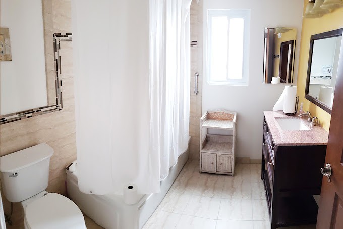 A bright and modern bathroom with a shower, sink, and natural lighting.