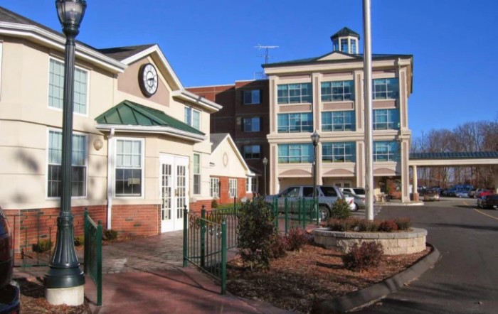 A commercial office building with multiple floors and a smaller adjacent structure on a clear day.