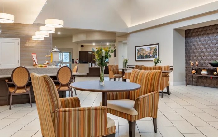 A cozy and well-lit hotel dining area with striped chairs and round tables.
