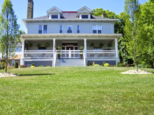 A charming blue house with a welcoming front porch and lush green lawn.