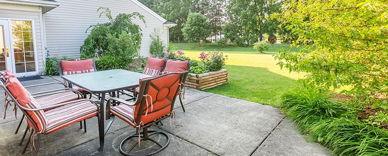 A cozy backyard patio with outdoor seating and a lush green lawn.