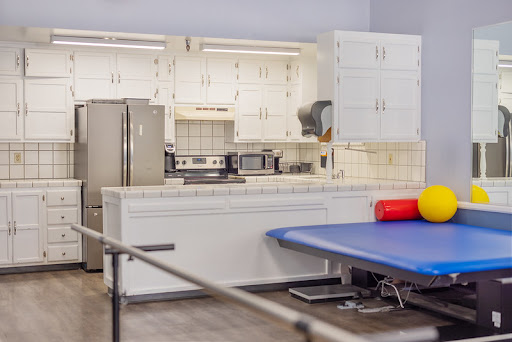 A well-equipped kitchen area in a rehabilitation setting, featuring modern appliances and exercise equipment.