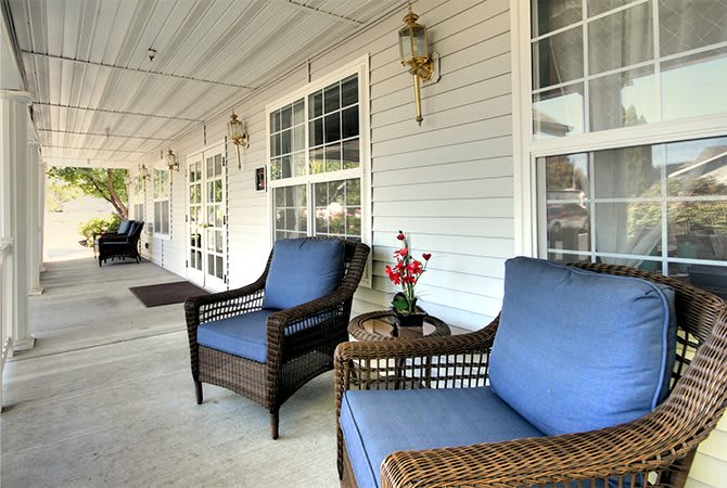 A cozy porch with wicker chairs and blue cushions, perfect for relaxation.