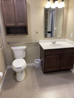 A clean and organized bathroom with a toilet, sink, and cabinet.