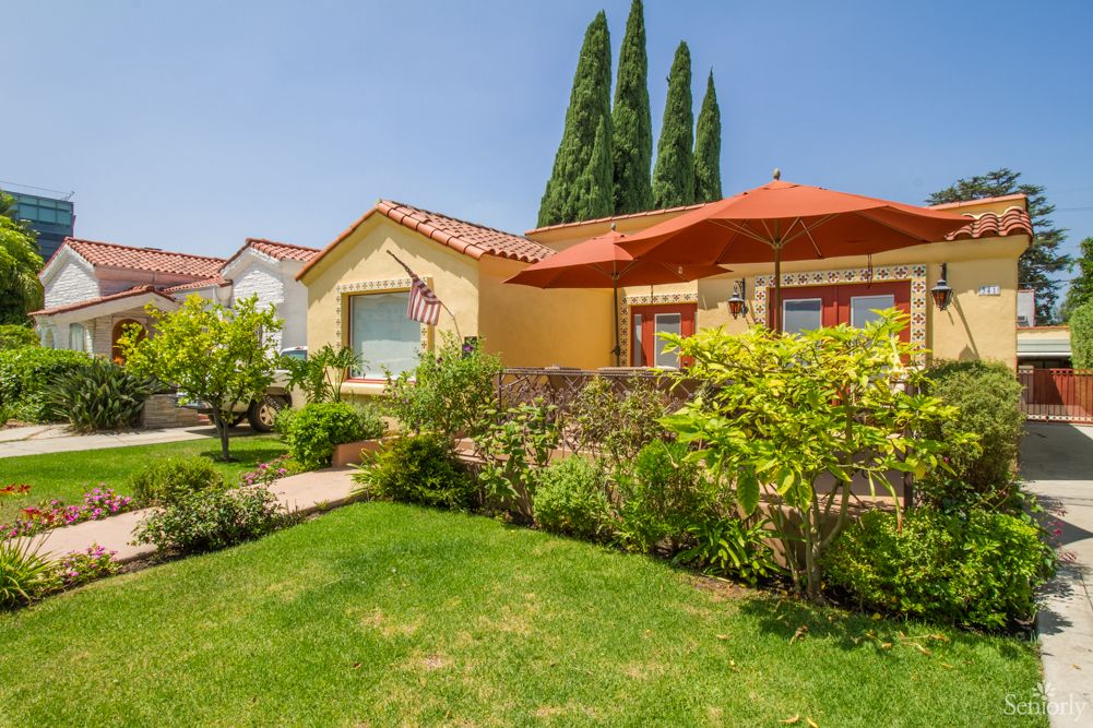 A charming house with a well-maintained garden and patio umbrella on a sunny day.