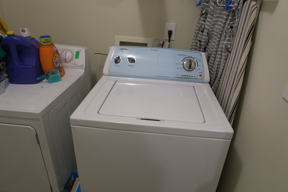 A classic top-loading washing machine in a laundry room setting.