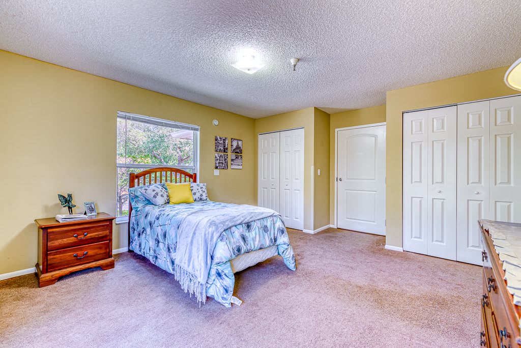 A cozy bedroom with a bed, carpeted floor, and a window providing natural light.