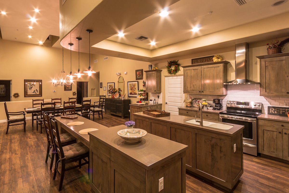 A modern kitchen with a spacious dining area, featuring wooden cabinets and elegant pendant lighting.