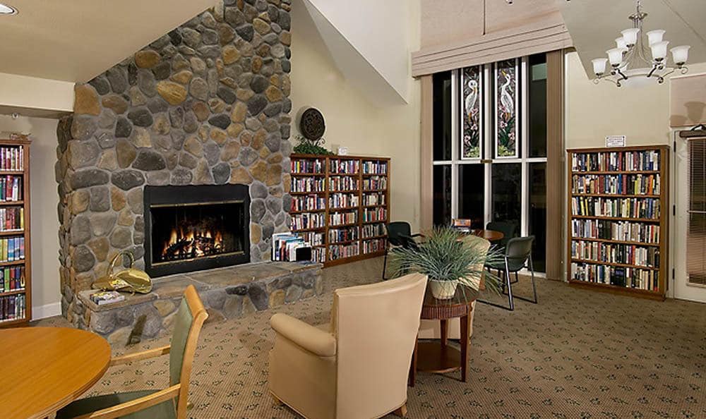 A cozy living room with a fireplace, bookshelf, and comfortable seating.
