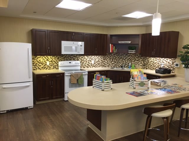 A modern kitchen with a central island, dark cabinets, and a stylish backsplash.