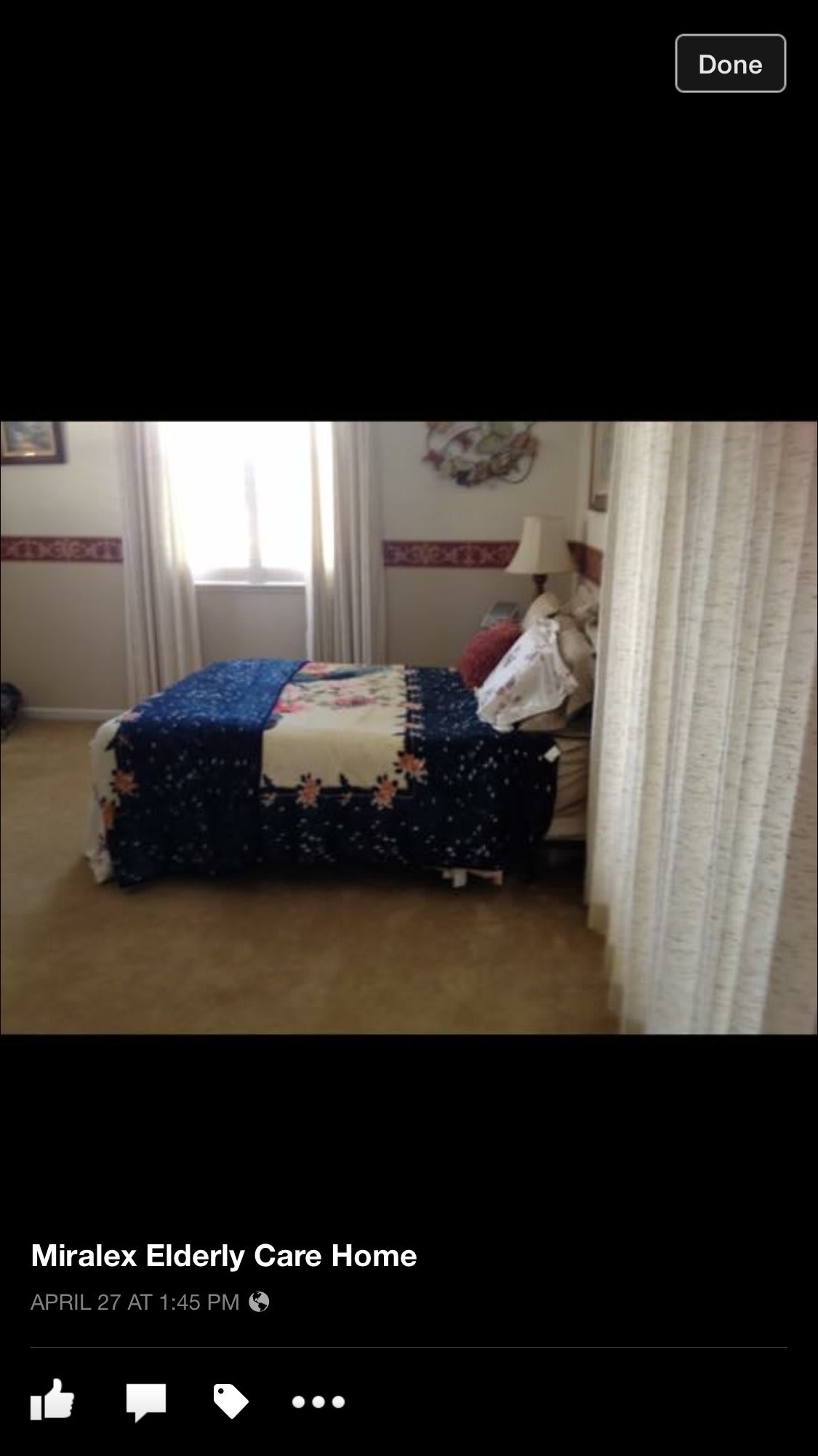 A cozy bedroom featuring a neatly made bed with patterned bedding, illuminated by natural light from a window with curtains.