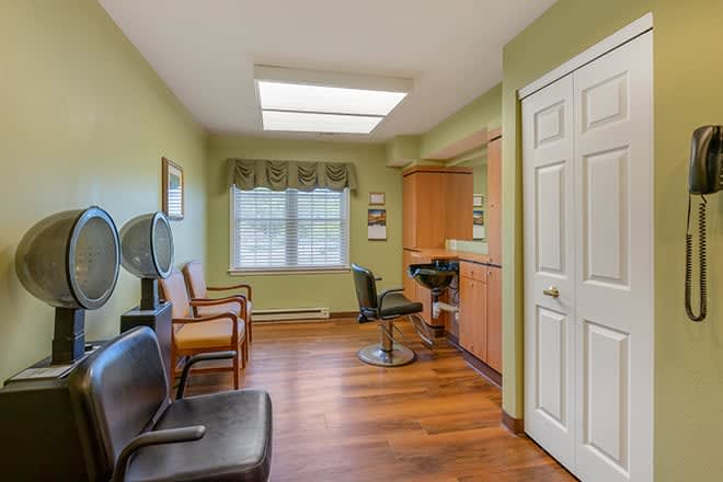 A cozy hair salon with modern decor featuring wooden floors and green walls.