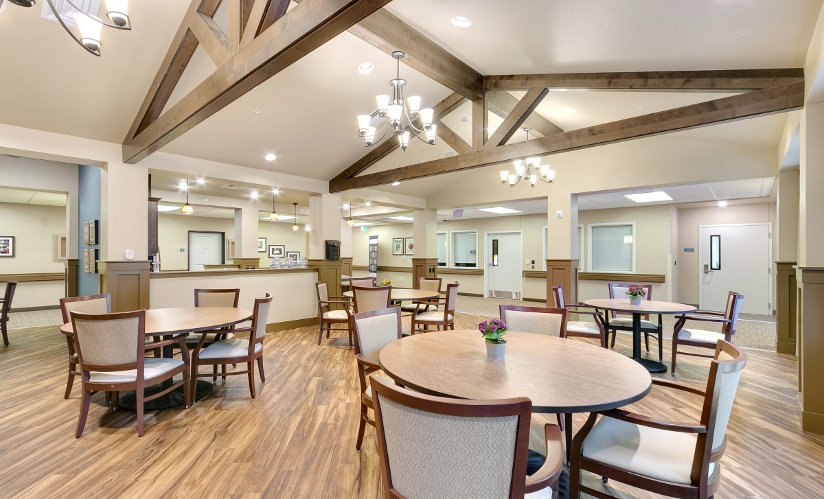 A spacious dining area with wooden tables, chairs, and elegant chandeliers.