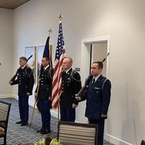 An honor guard stands in formation during a ceremonial event, holding flags in a solemn setting.