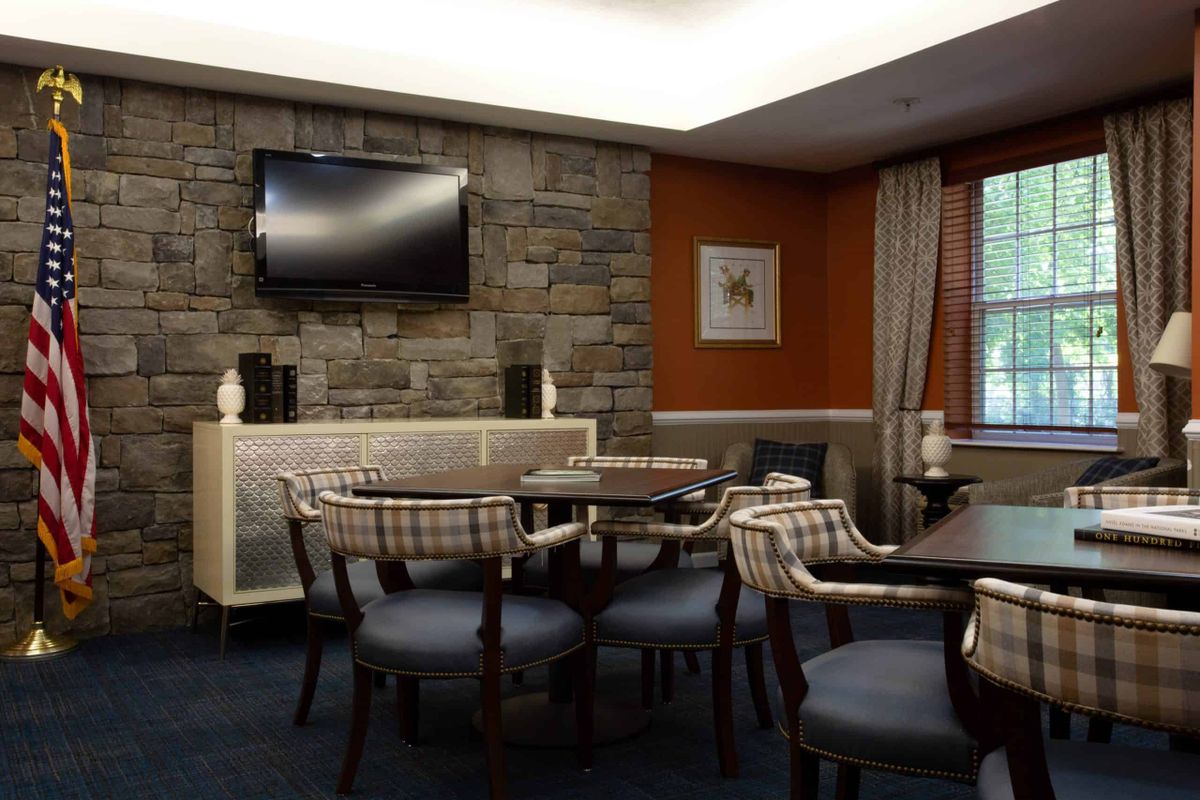 A modern lounge area featuring a stone wall, television, and comfortable seating with tables.