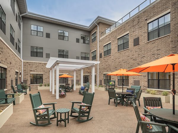 A patio area with seating, umbrellas, and a modern building backdrop.