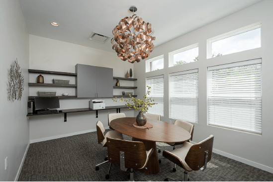 A modern office conference room with a round table and stylish chandelier.