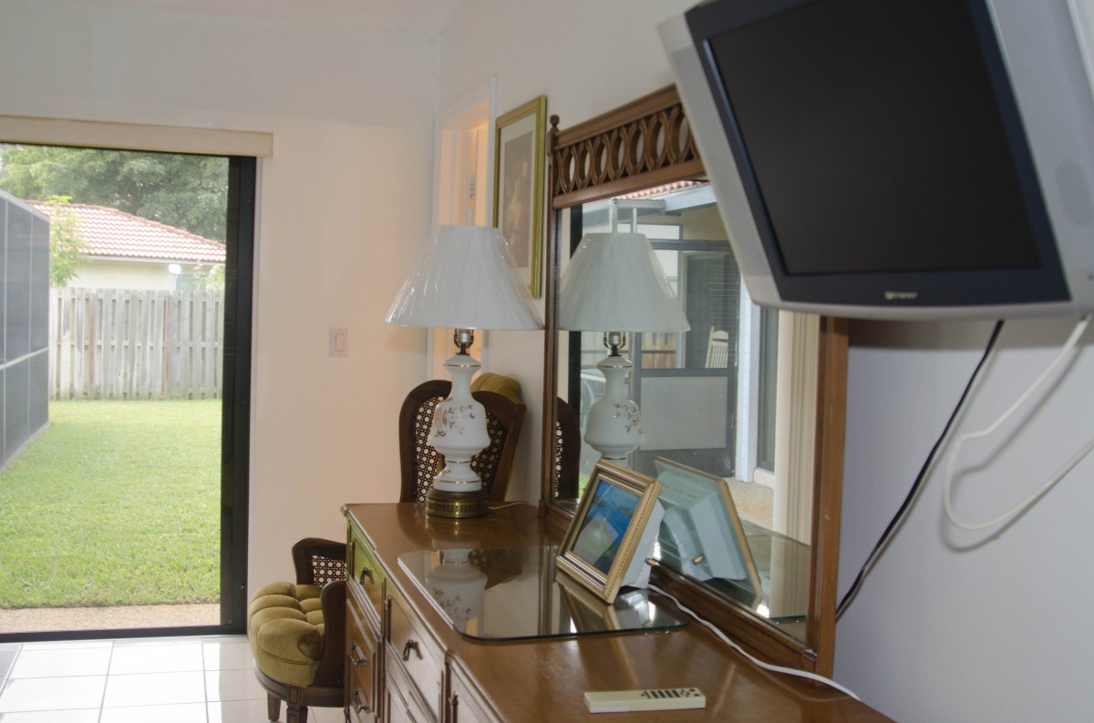A cozy bedroom with a dresser, mirror, and a wall-mounted TV.