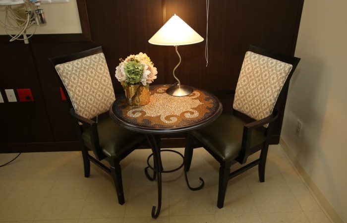 A cozy indoor setting with a round table, two chairs, and a lamp.