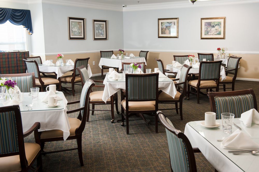 An elegantly arranged dining room with white tablecloths and neatly set tables and chairs.