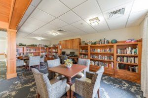 A cozy library room with bookshelves, tables, and chairs arranged for reading and studying.