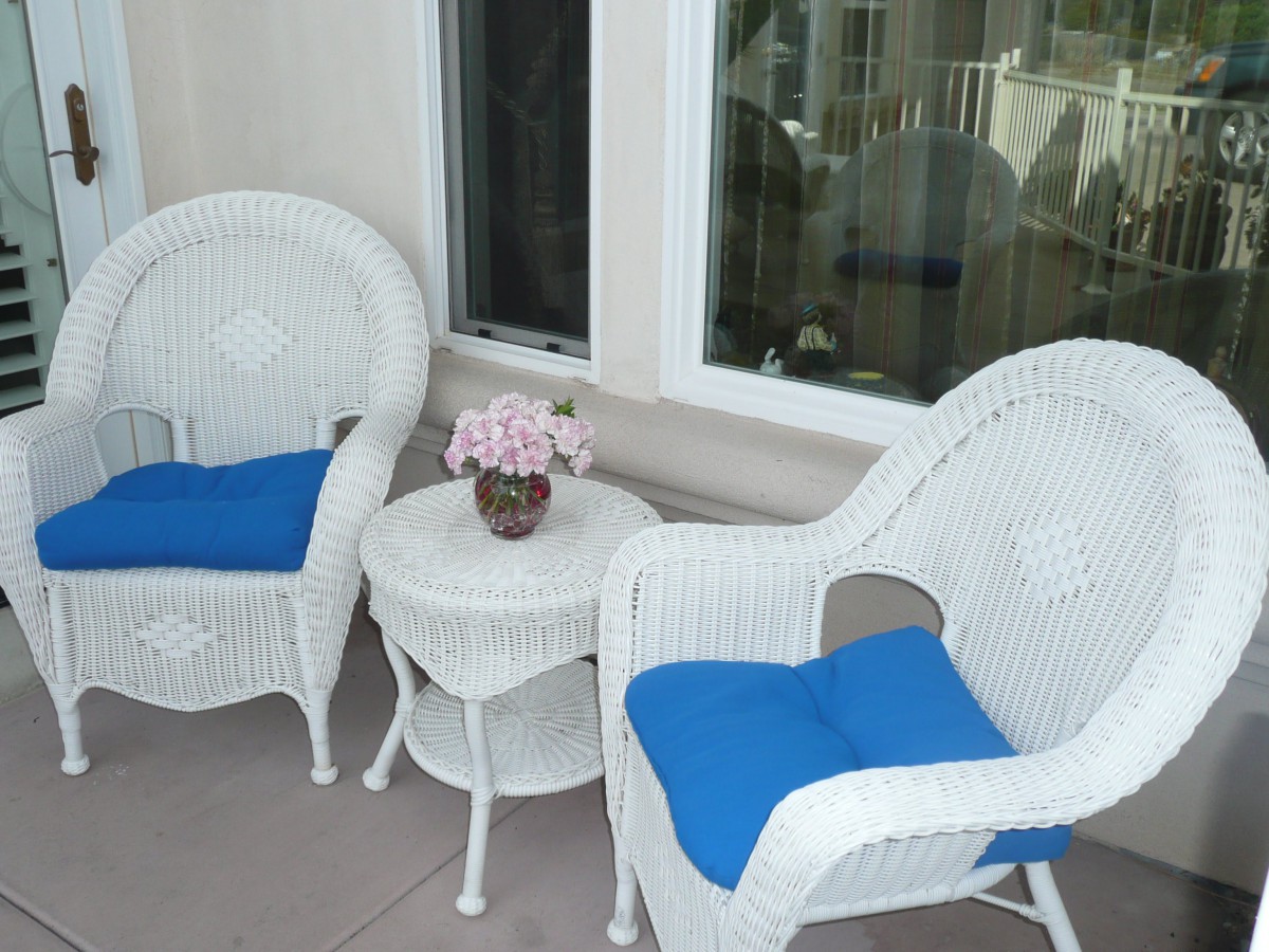A cozy patio setup with wicker chairs, a small table, and blue cushions.