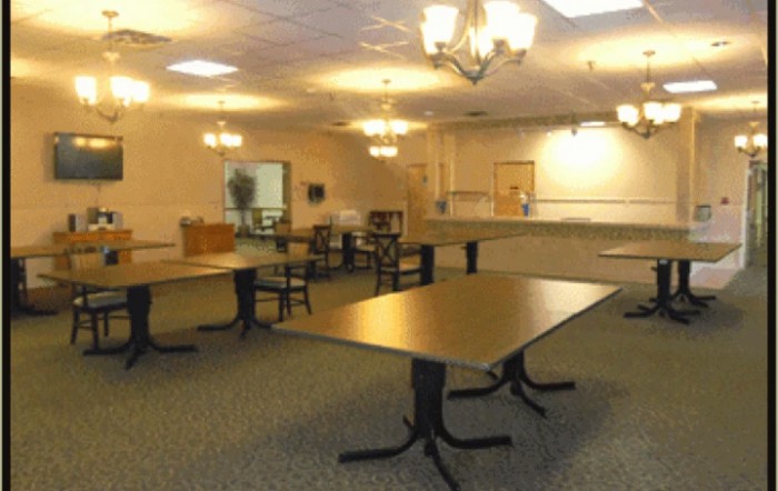 An empty room with tables, chairs, and chandeliers.