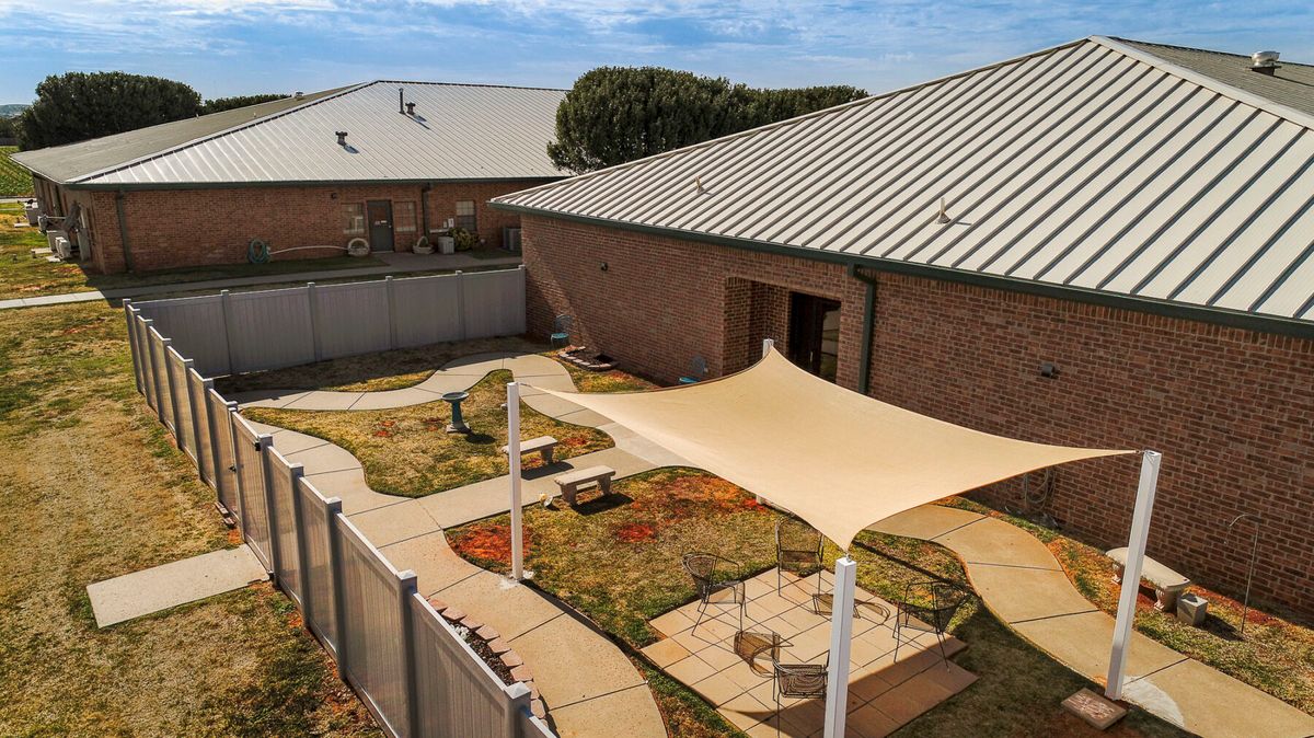 A backyard area with a shade structure, garden, and paved pathways.