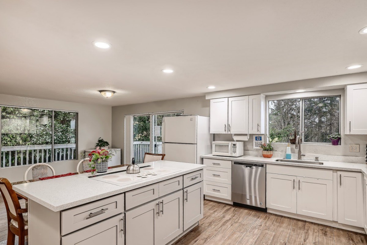 A modern kitchen with white cabinets, a spacious island, and wood flooring.