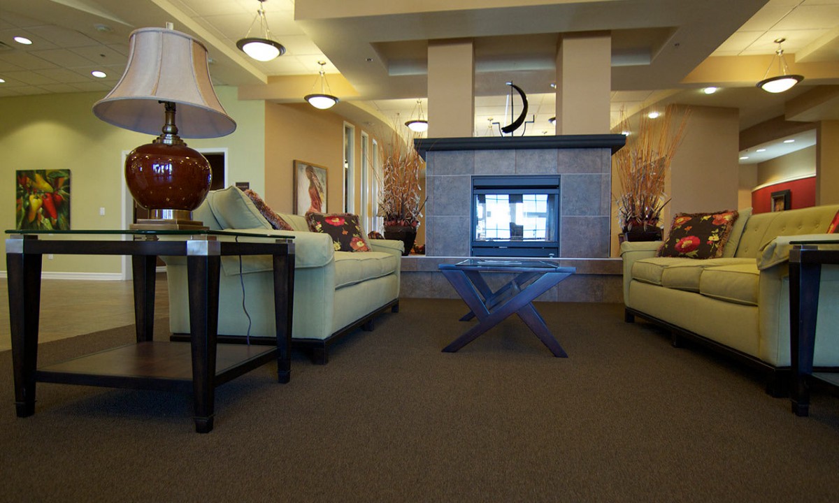 A cozy living room with modern decor featuring sofas, a central fireplace, and ambient lighting.