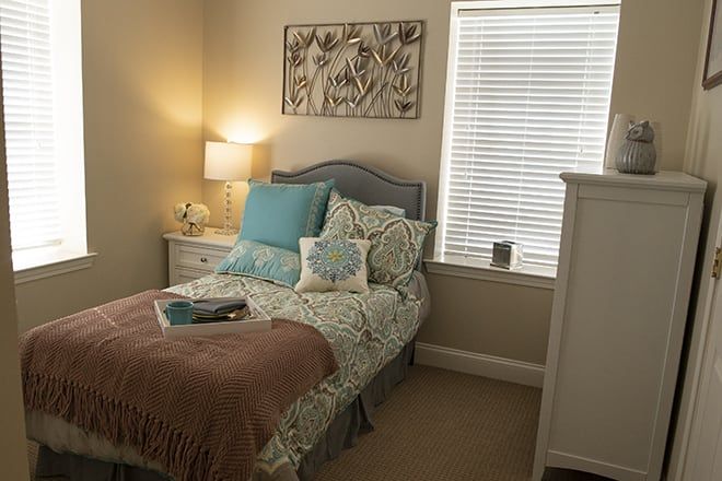 A cozy, well-decorated bedroom with a bed, lamp, and artwork on the wall.