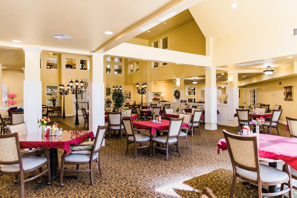 A spacious and well-lit dining room with neatly arranged tables and chairs.