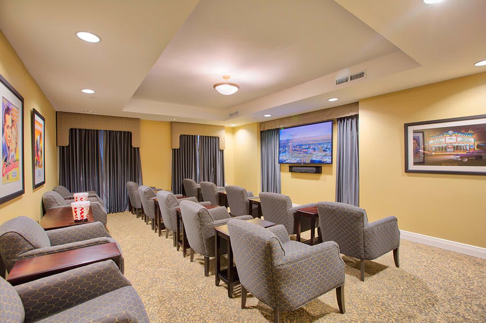 A cozy home theater setup with multiple rows of comfortable chairs facing a wall-mounted television.