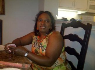 A person sitting at a table indoors and smiling.