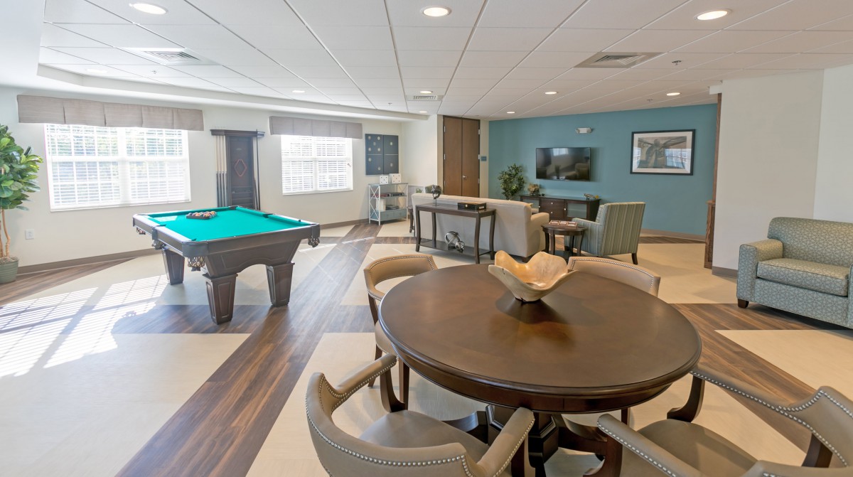 A modern game room featuring a pool table, seating area, and television.
