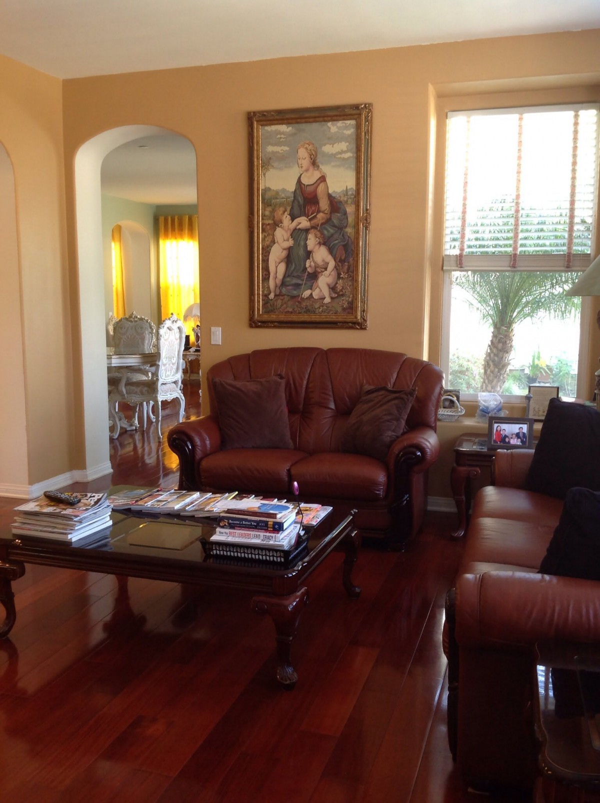 A cozy living room with leather sofas, a wooden coffee table, and a large painting on the wall.