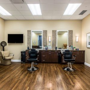 A well-lit barbershop interior with two chairs and mirrors.