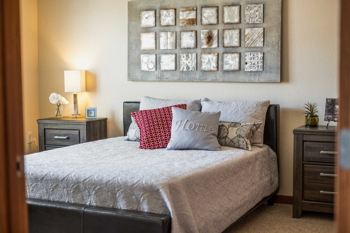 A cozy bedroom with a neatly made bed, decorative pillows, and wall art above the headboard.