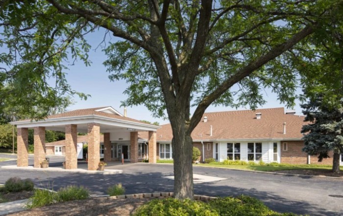 A view of a building exterior with a large tree in the foreground.
